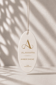 Alamara Amber Smoke Car Fragrance hanging against a neutral background with shadows.