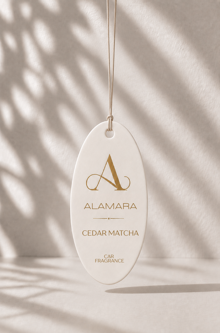 Alamara Cedar Matcha car fragrance hanging against a neutral background with shadows.