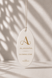 Alamara Glowing Star Car Fragrance hanging against a neutral background with shadows.
