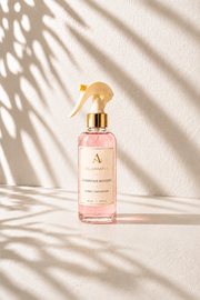 Pink spray bottle with gold nozzle on a light background