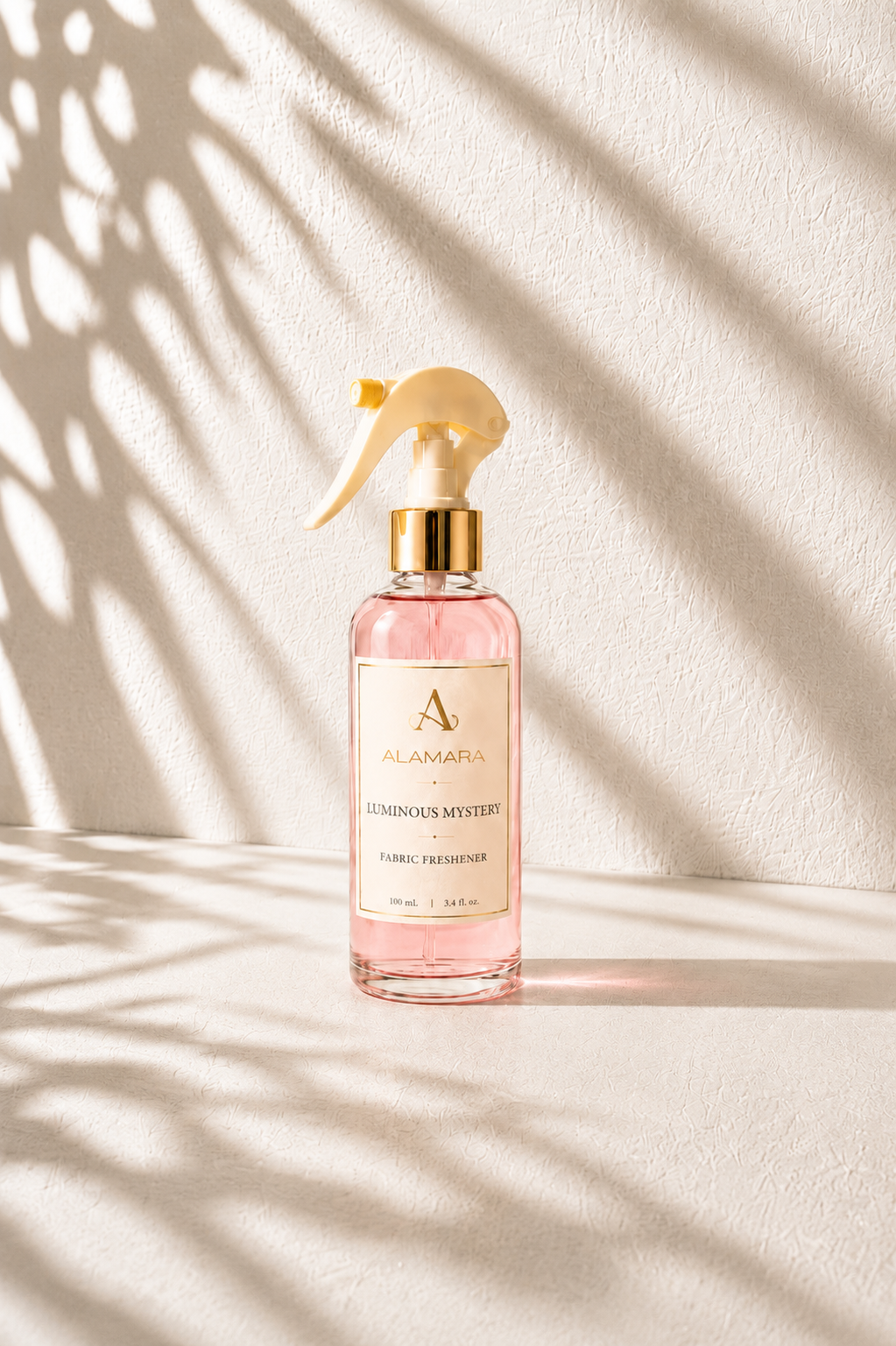 Pink spray bottle with gold nozzle on a light background