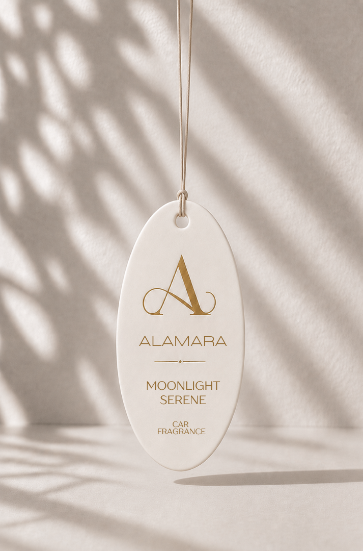 Alamara Moonlight Serene car fragrance hanging against a neutral background with shadows.
