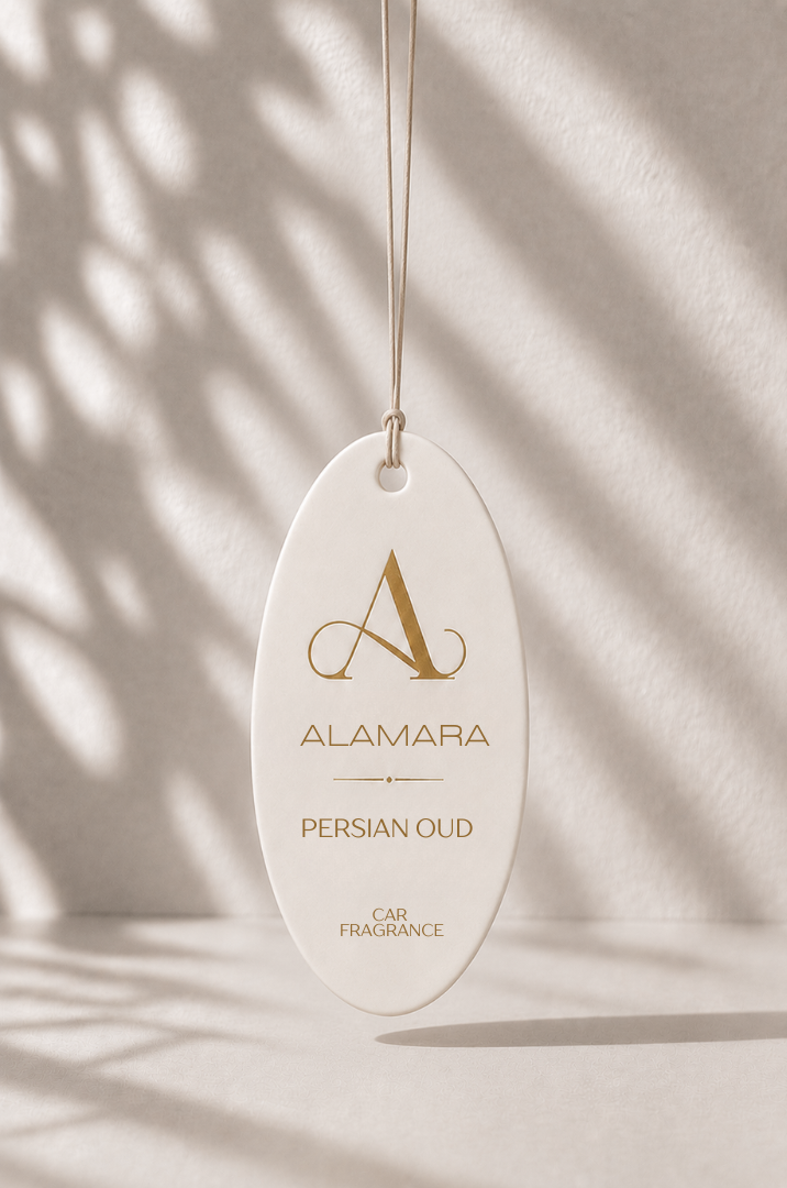 Alamara Persian Oud car fragrance hanging against a neutral background with leaf shadows.